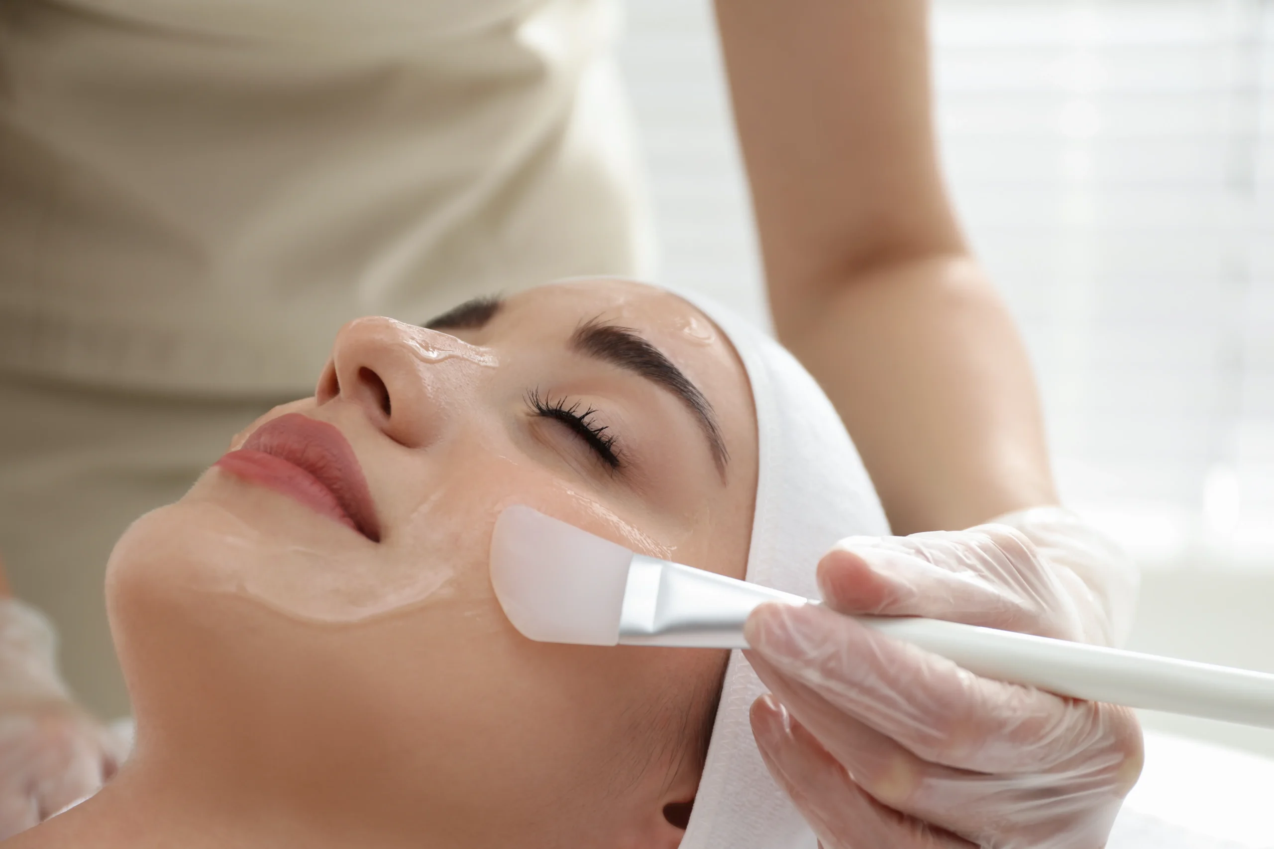 a person applying a mask on a woman's face