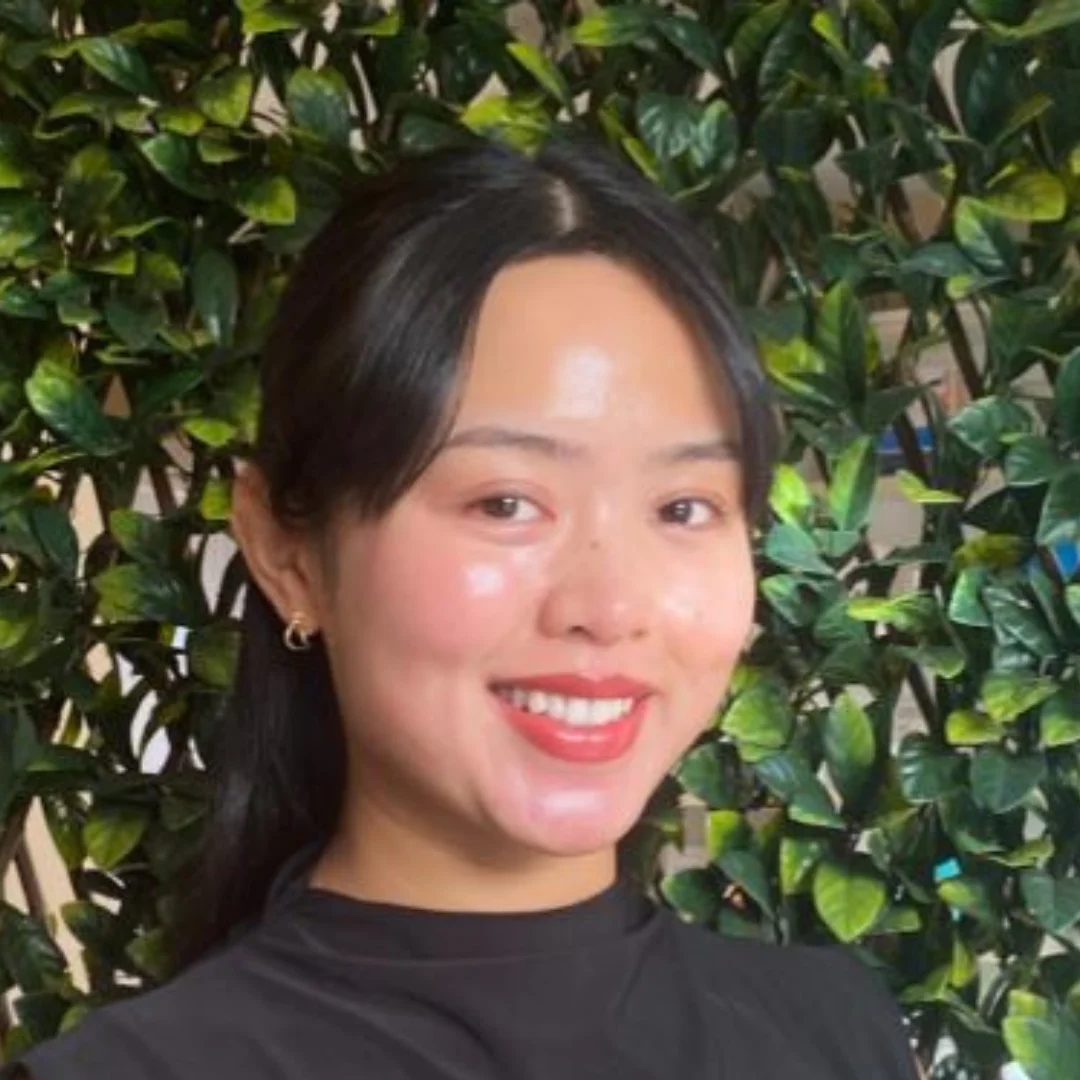 a woman smiling in front of a bush