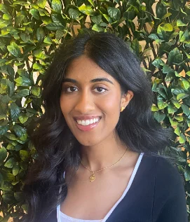 a woman smiling in front of a bush