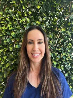 a woman smiling in front of a bush